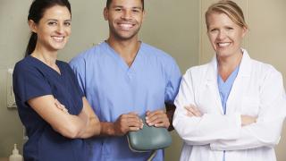 Kolme hammaslääkäriä eri etnisistä taustoista seisoo yhdessä