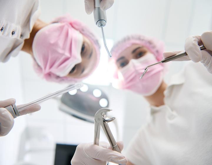 Hammaslääkäri ja hammashoitaja hoitamassa potilasta suojavarusteissa 