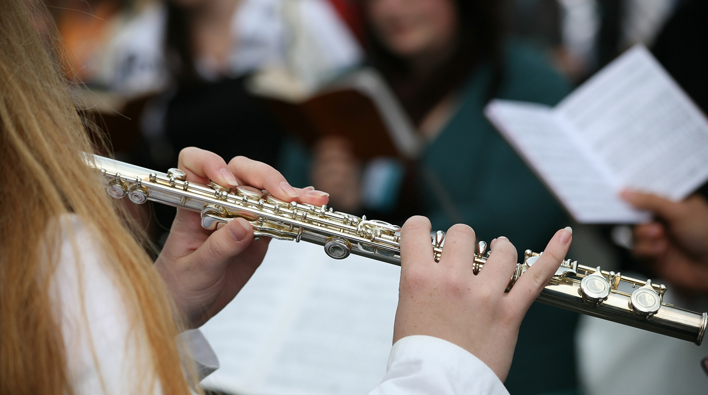 Naismuusikko soittaa huilua sinfoniaorkesterissa