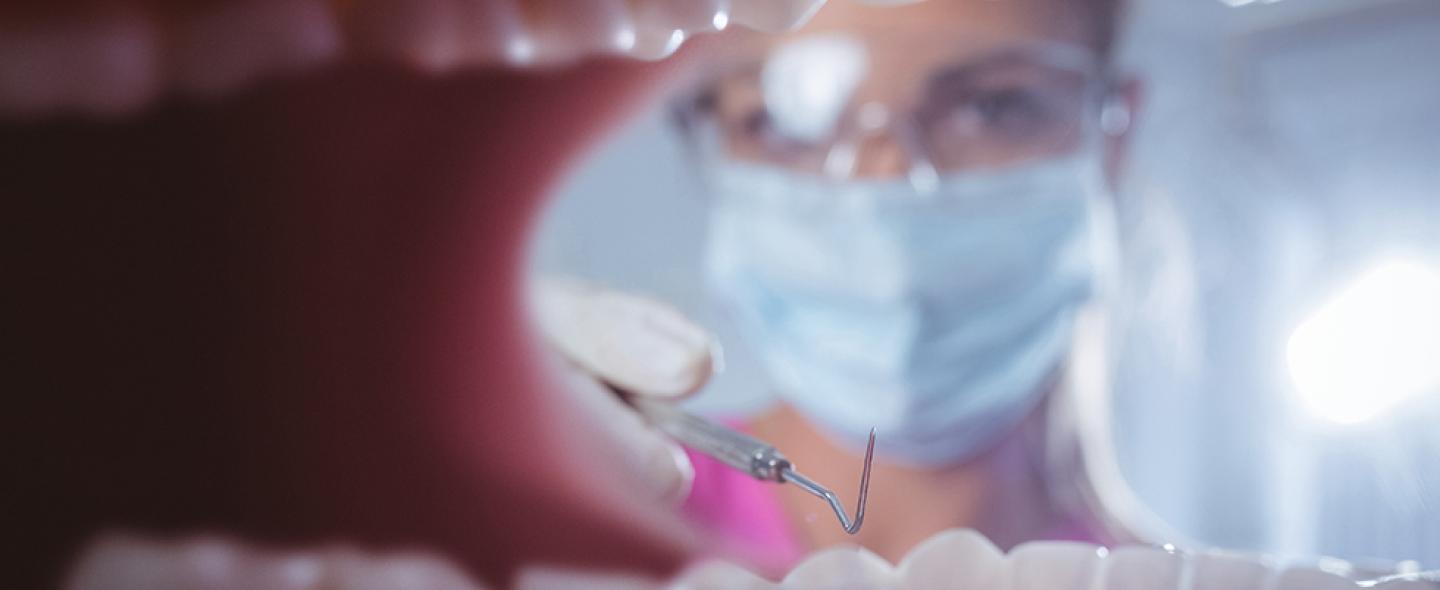 Hammaslääkäri katsoo potilaan suuhun