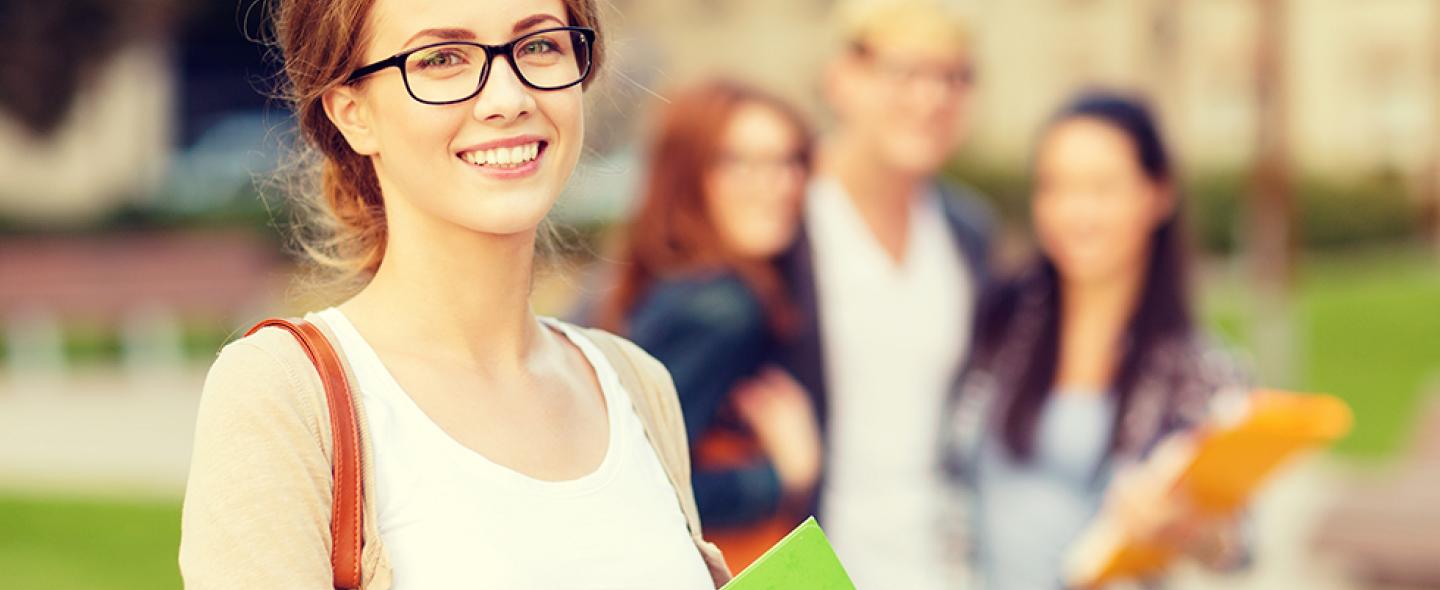 Ryhmä opiskelijoita seisoo juttelemassa yliopiston pihalla