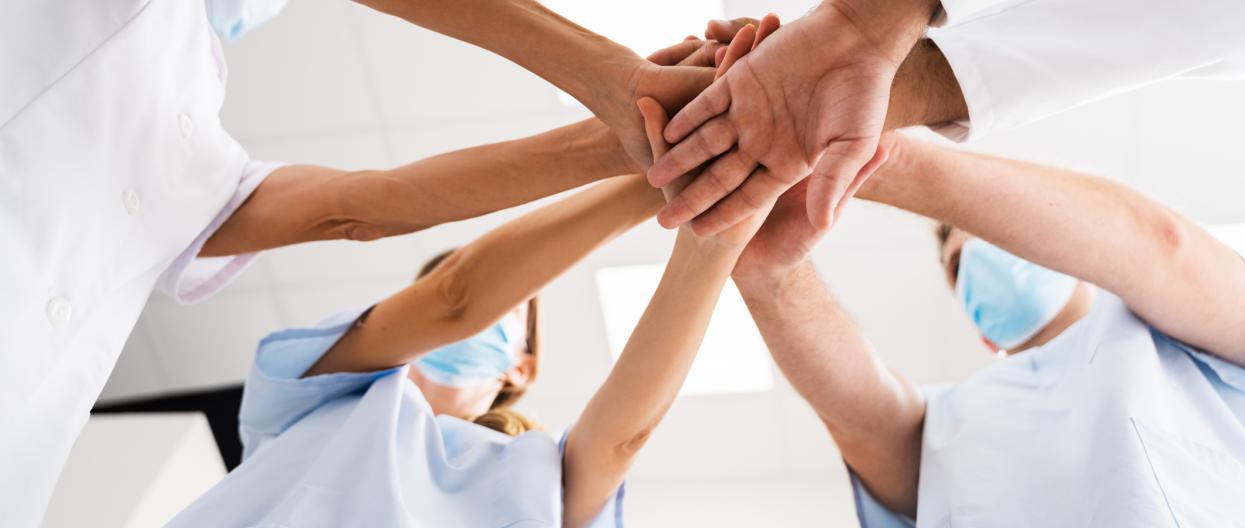Terveydenhuollon ammattilaiset seisovat ryhmänä kädet yhdessä