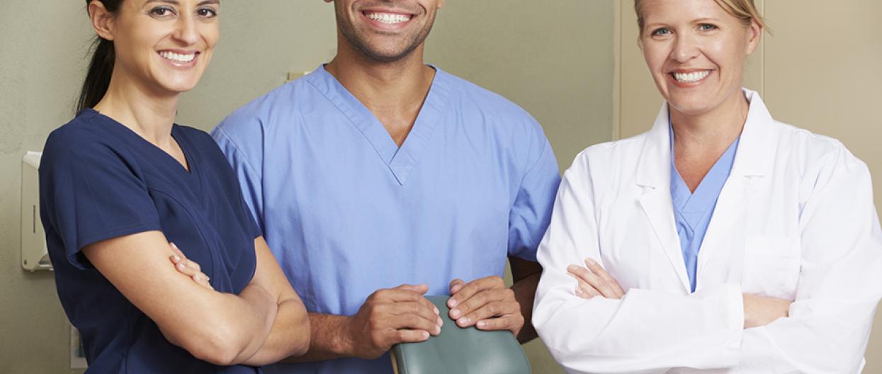 Kolme hammaslääkäriä eri etnisistä taustoista seisoo yhdessä