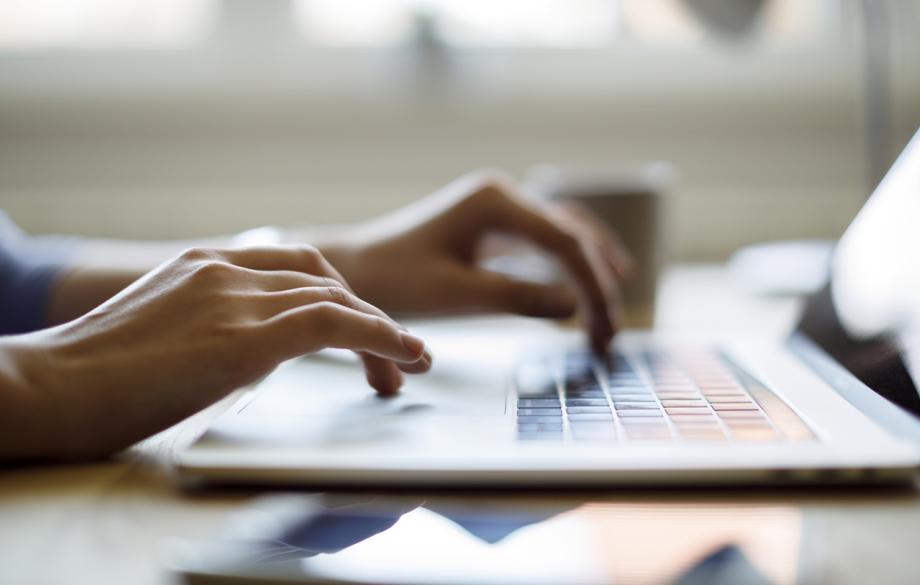 Tietokoneella työskentelevä ihminen lähikuvassa